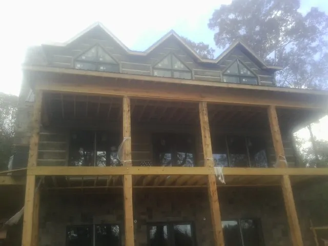 Dormers and porch framing on a large log home under construction — Roof Coating work by our crew in Rockville